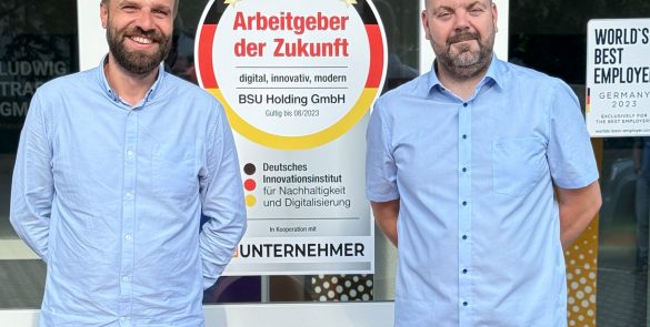 Die neuen Gesch&auml;ftsf&uuml;hrer der BSU Holding, Matthias Gommlich und Andr&eacute; Tischler, stehen vor dem Firmensitz mit gro&szlig;em BSU-Logo und Auszeichnung &sbquo;Arbeitgeber der Zukunft&lsquo;.