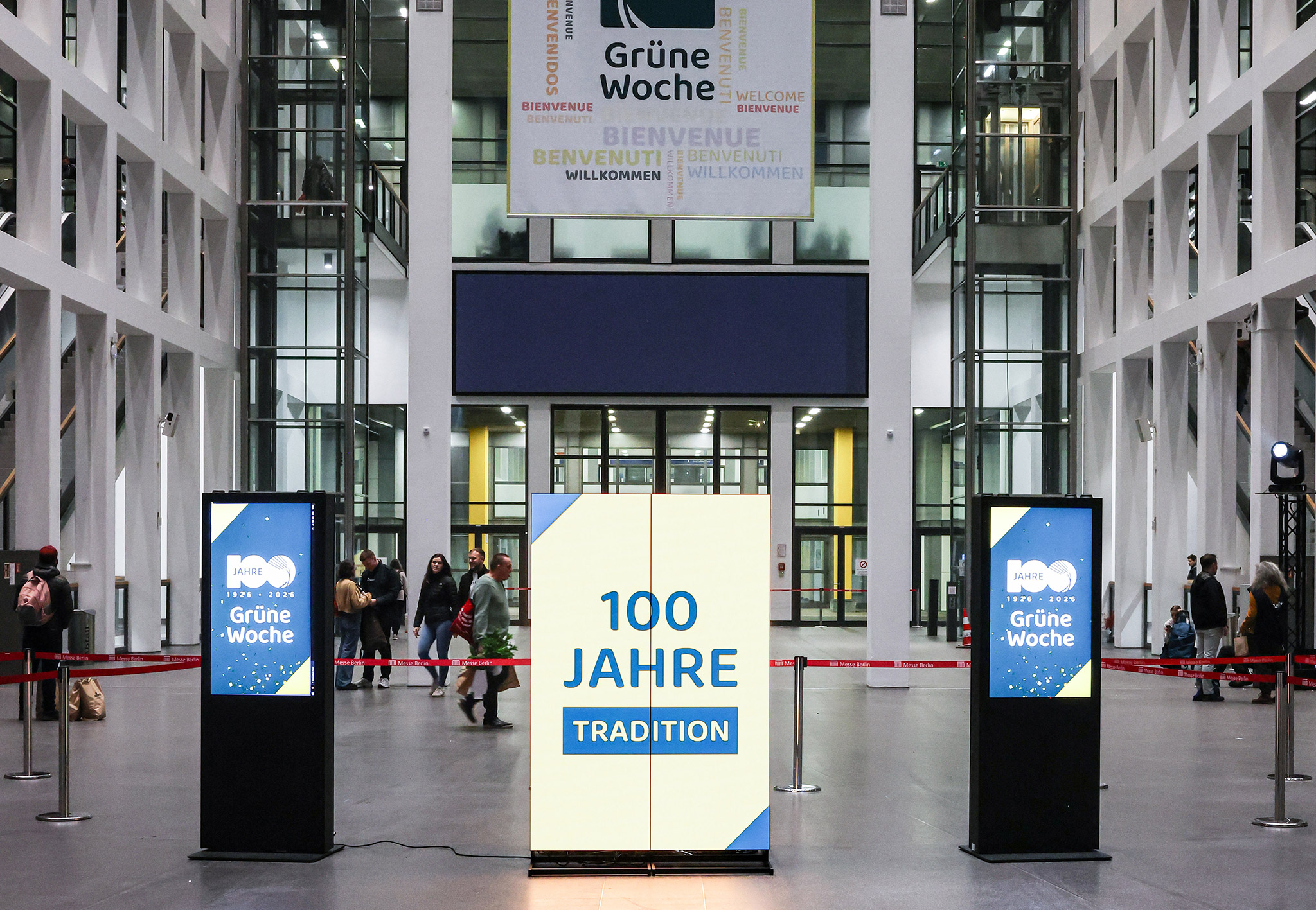 Eingangshalle der Internationalen Grünen Woche in Berlin mit Banner „Grüne Woche“ und Display „100 Jahre Tradition“.